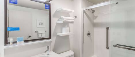 Un baño moderno con cabina de ducha de vidrio, lavabo y espejo.