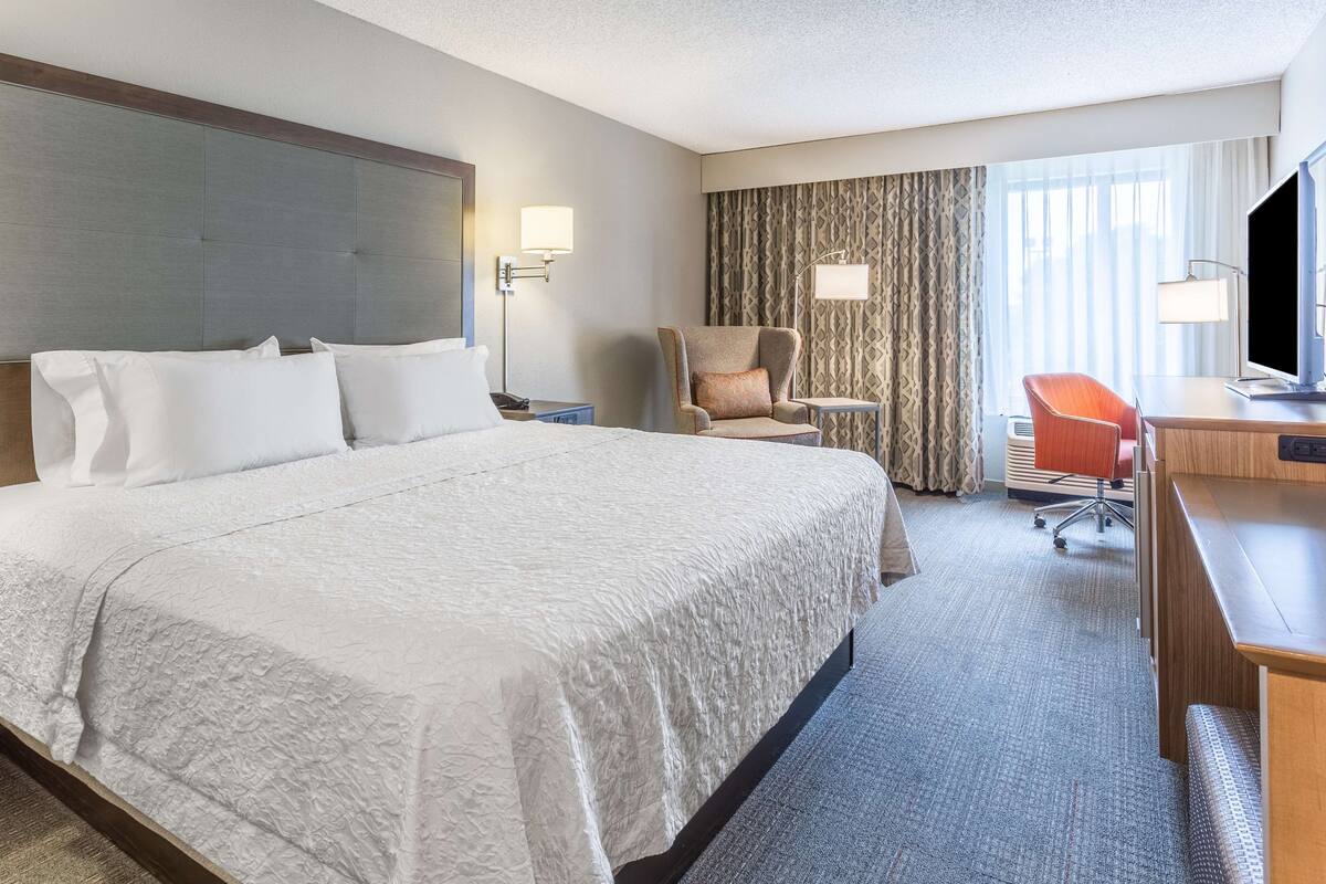 Une chambre d’hôtel avec un grand lit, un bureau avec un ordinateur, une chaise et un téléviseur.