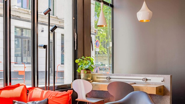 Un interior moderno con una zona de estar, una planta en maceta y vistas a la calle.