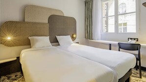 Una habitación de hotel con una cama grande, un escritorio y una silla.