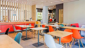 Un restaurante moderno con una zona de bar, varias mesas para comer y sillas coloridas.