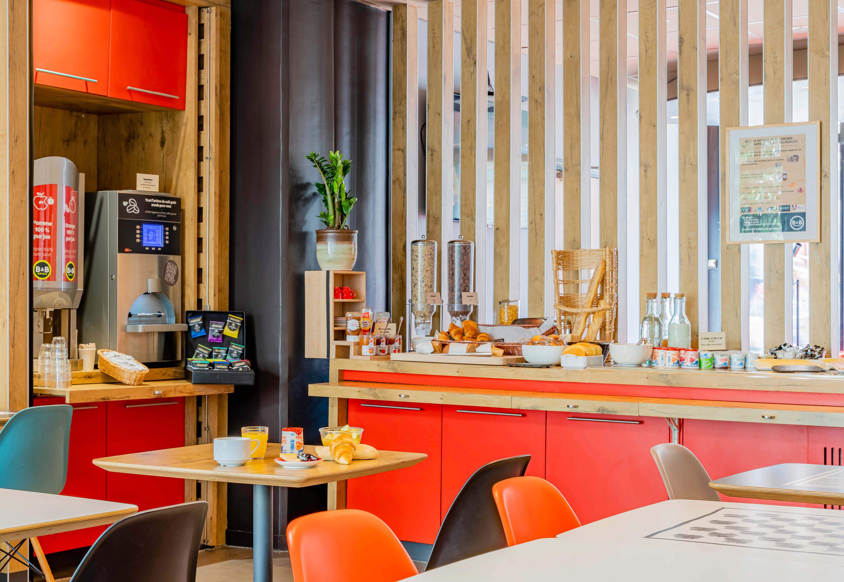 A modern cafe with a wooden counter, red cabinets, and a coffee machine.