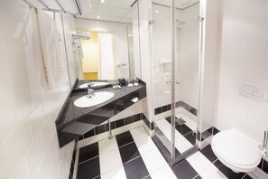 Un baño moderno con dos lavamanos, cabina de ducha de vidrio y un inodoro blanco.