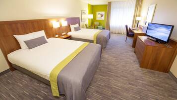 A hotel room with two beds, a desk with a computer, and a TV.