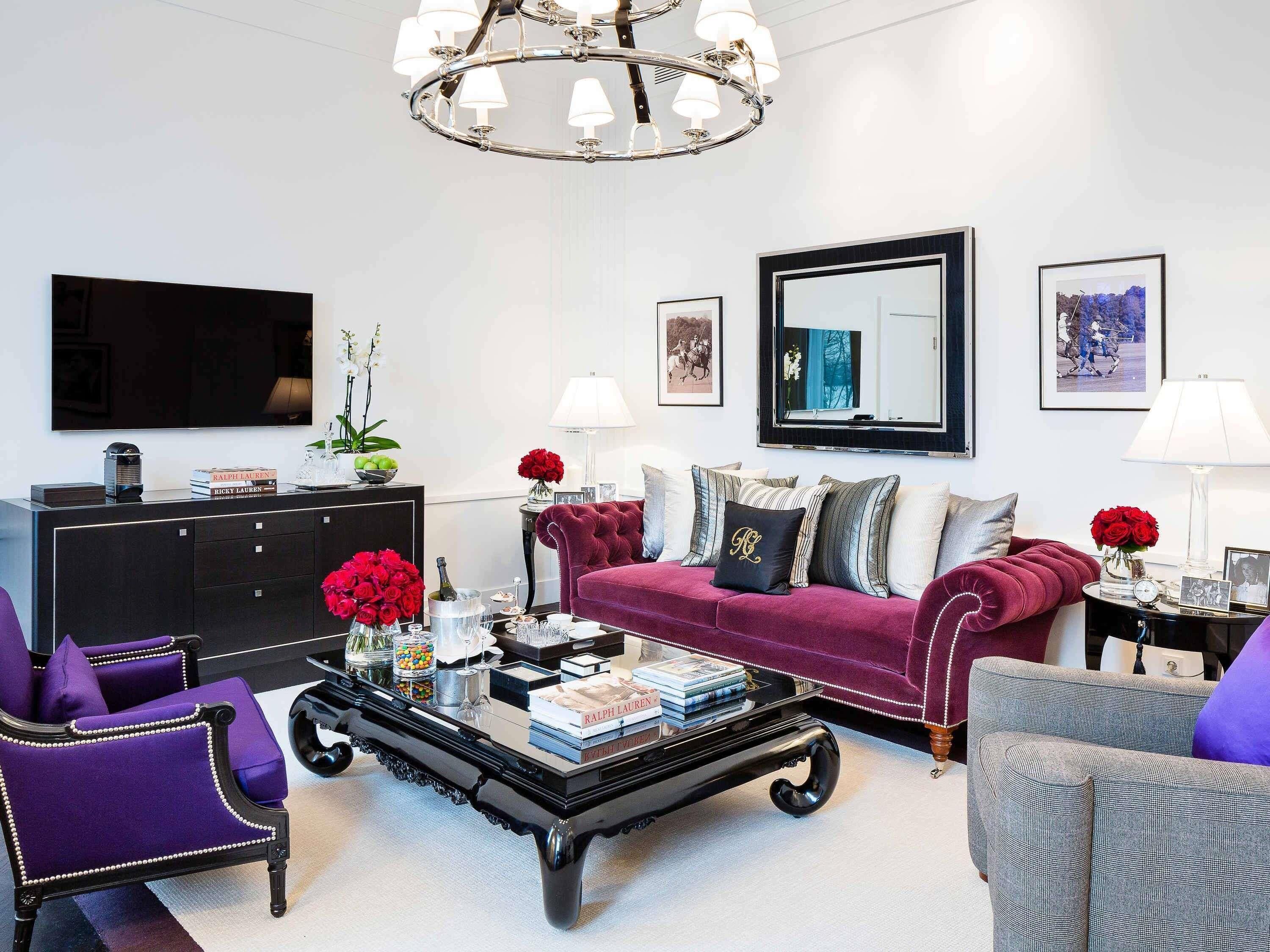 A modern living room with a black coffee table, a red sofa, and a purple armchair.