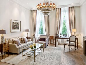 A well-lit living room with a chandelier, a sofa, a coffee table, and a fireplace. - Fairmont Hotel Vier Jahreszeiten Hamburg (Hamburg)