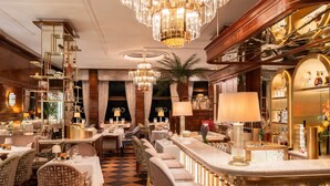 A bar area with a checkered floor, bar stools, and a bar counter. - Fairmont Hotel Vier Jahreszeiten Hamburg (Hamburg)