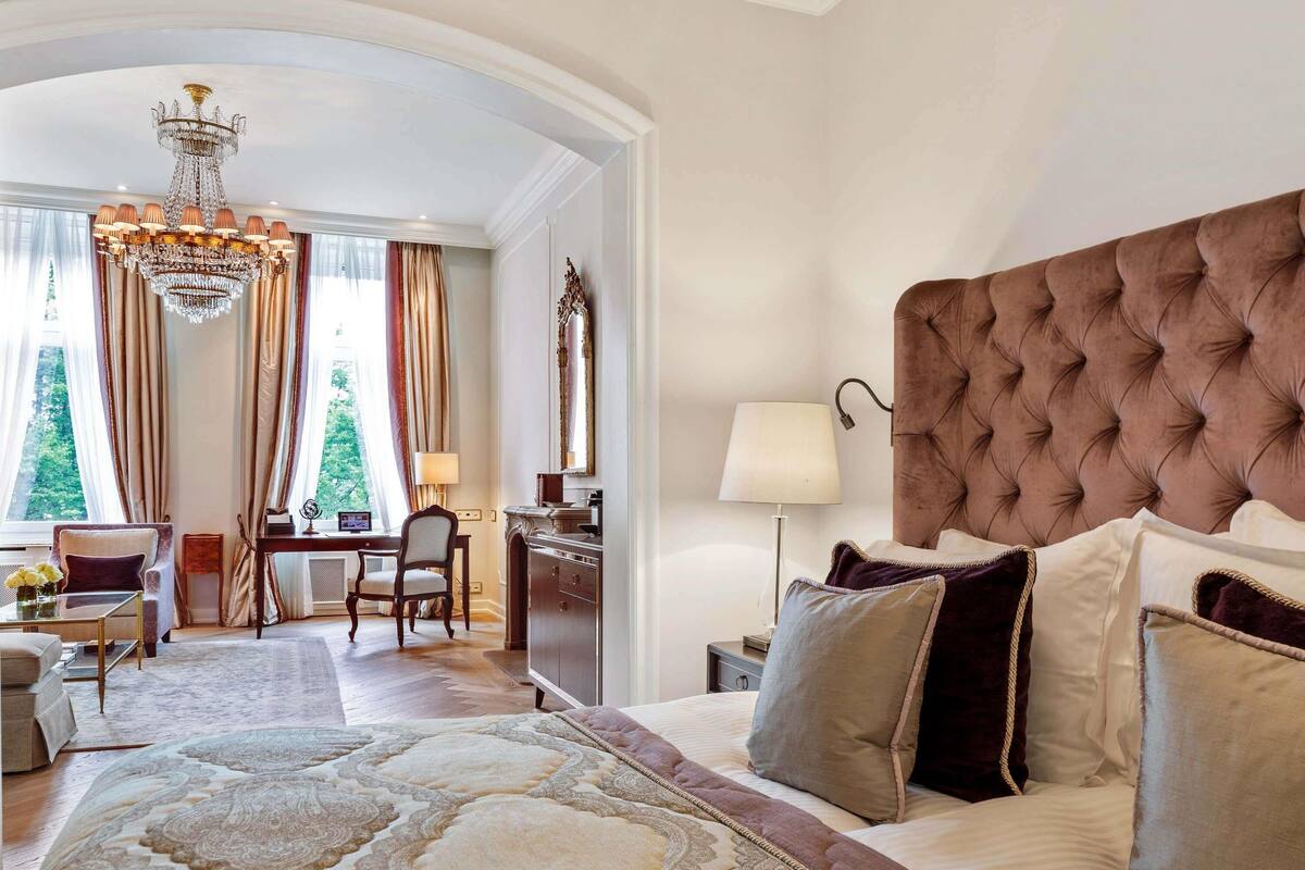 A hotel room with a large bed, a desk, and a chair.