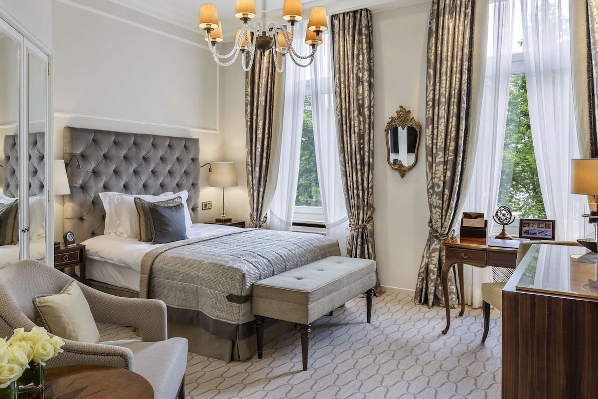 A bedroom with a tufted headboard, a large bed, a desk, and a chair.