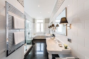 A modern bathroom with a glass shower enclosure, a large mirror, and a vanity with a sink and mirror. - Fairmont Hotel Vier Jahreszeiten Hamburg (Hamburg)