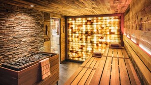 A sauna room with wooden benches, a stone wall, and a wooden ceiling. - Fairmont Hotel Vier Jahreszeiten Hamburg (Hamburg)