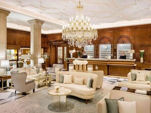 A luxurious hotel lobby with a grand chandelier, plush seating, a reception desk, and a concierge area. - Fairmont Hotel Vier Jahreszeiten Hamburg (Hamburg)