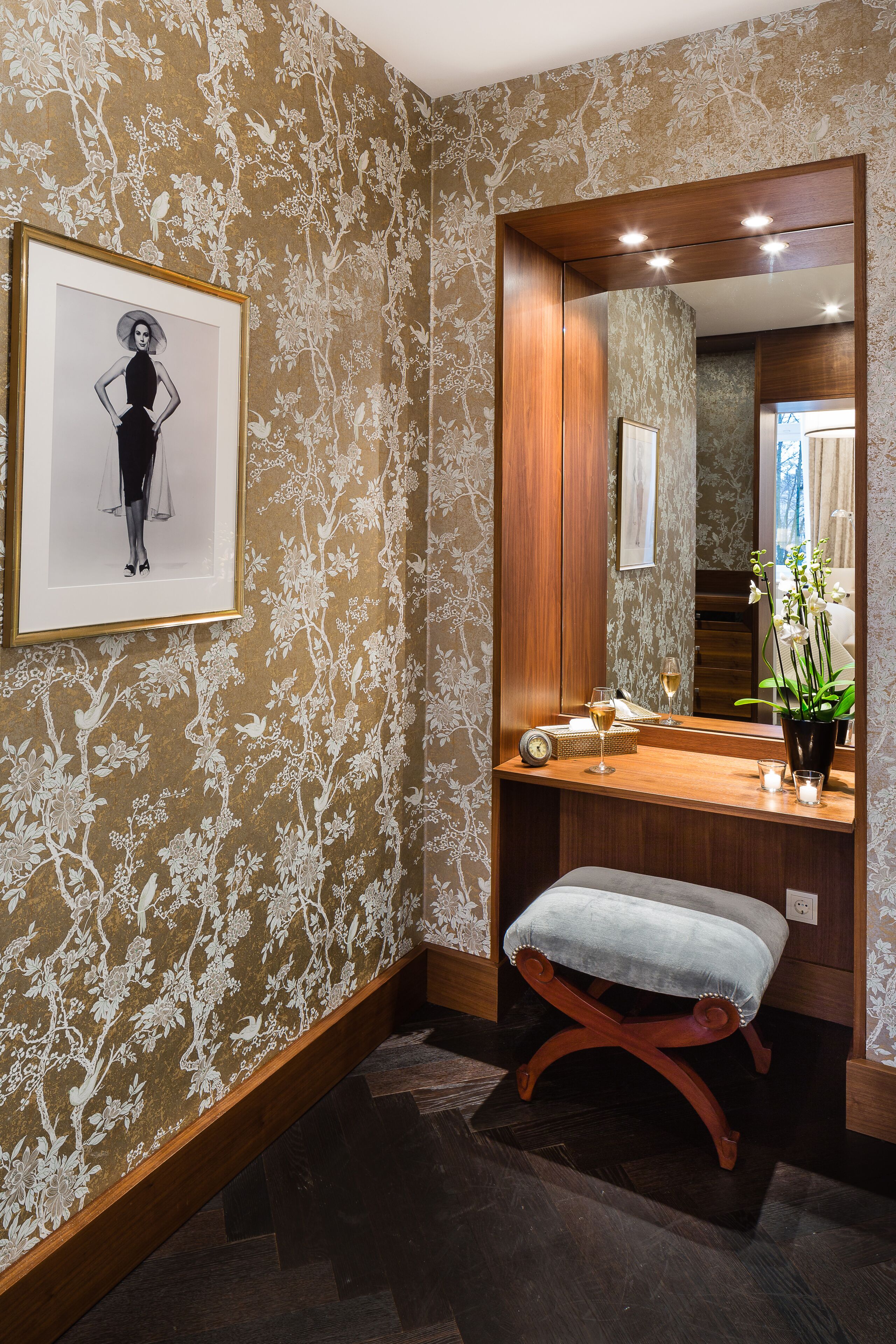 A bathroom with a wooden vanity, a framed picture on the wall, a bench, and a mirror.