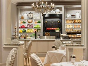 A well-lit kitchen area with a clock, a chandelier, and various food items on shelves. - Fairmont Hotel Vier Jahreszeiten Hamburg (Hamburg)