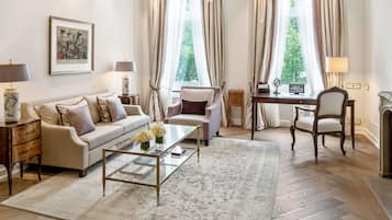 A well-lit room with a chandelier, a sofa, a coffee table, and a desk with a chair.