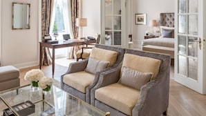 A hotel room with a sofa, a desk, a bed, and a glass door. - Fairmont Hotel Vier Jahreszeiten Hamburg (Hamburg)