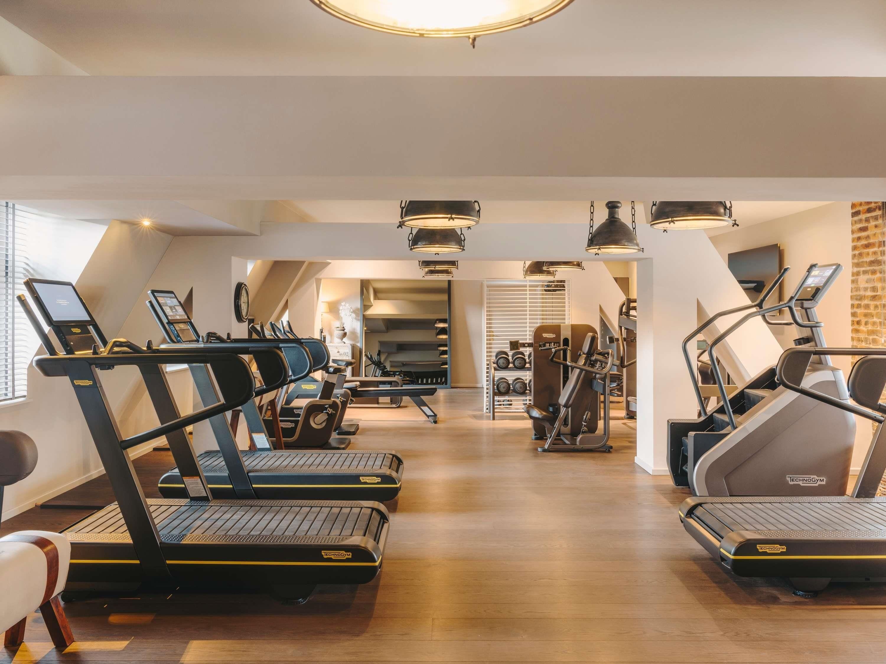 Un gimnasio con cintas de correr, máquinas de pesas y un espejo.