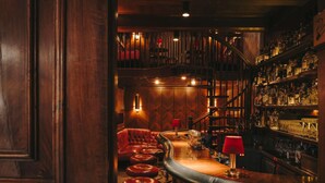 A bar area with leather stools, a curved bar counter, and a wooden staircase. - Fairmont Hotel Vier Jahreszeiten Hamburg (Hamburg)
