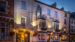 A historic building with a sign reading "Three Swans Hotel" and a traditional pub sign above the entrance. - The Three Swans Hotel, Market Harborough, Leicestershire (Market Harborough)