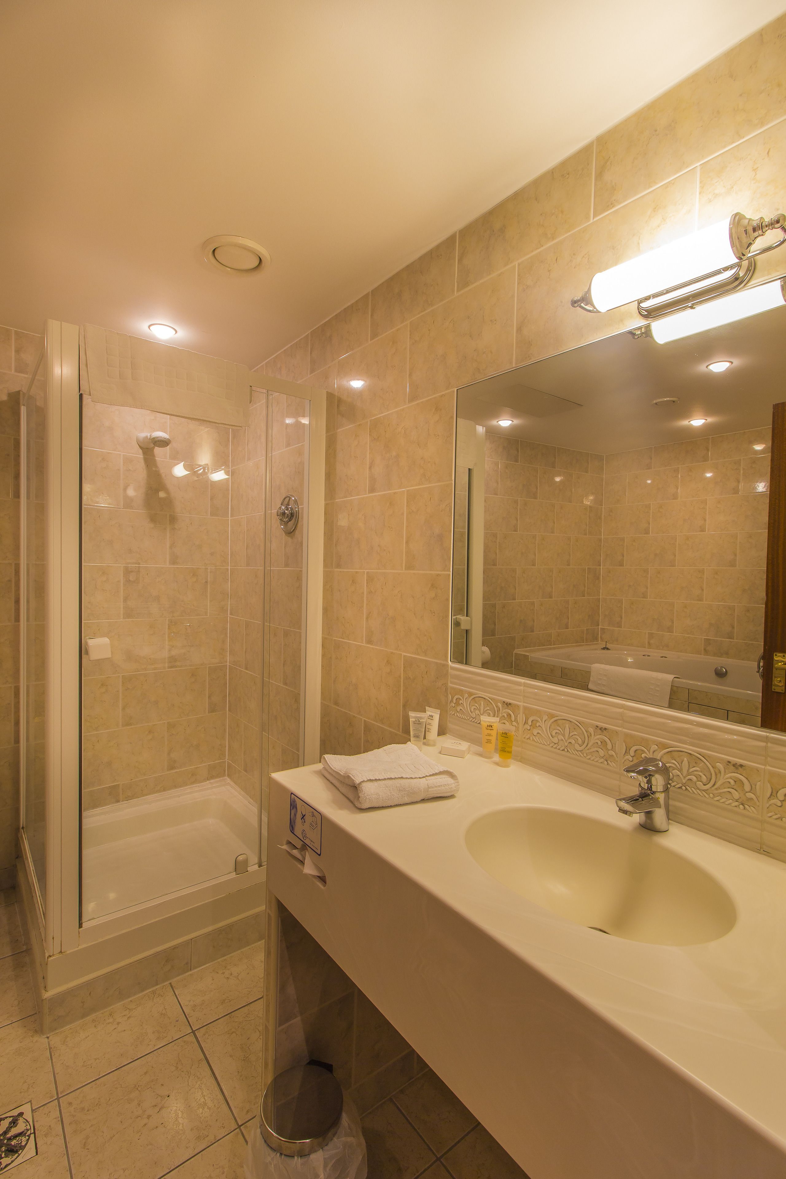 A bathroom with a large sink, mirror, and shower area.