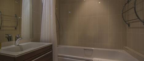 A bathroom with a double sink vanity, a bathtub, and a shower.