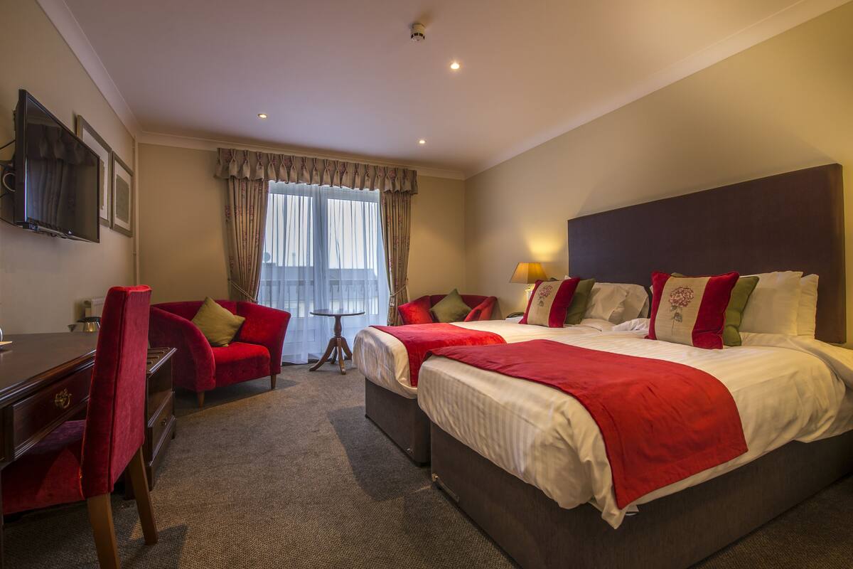 A hotel room with two beds, a desk, and a chair.