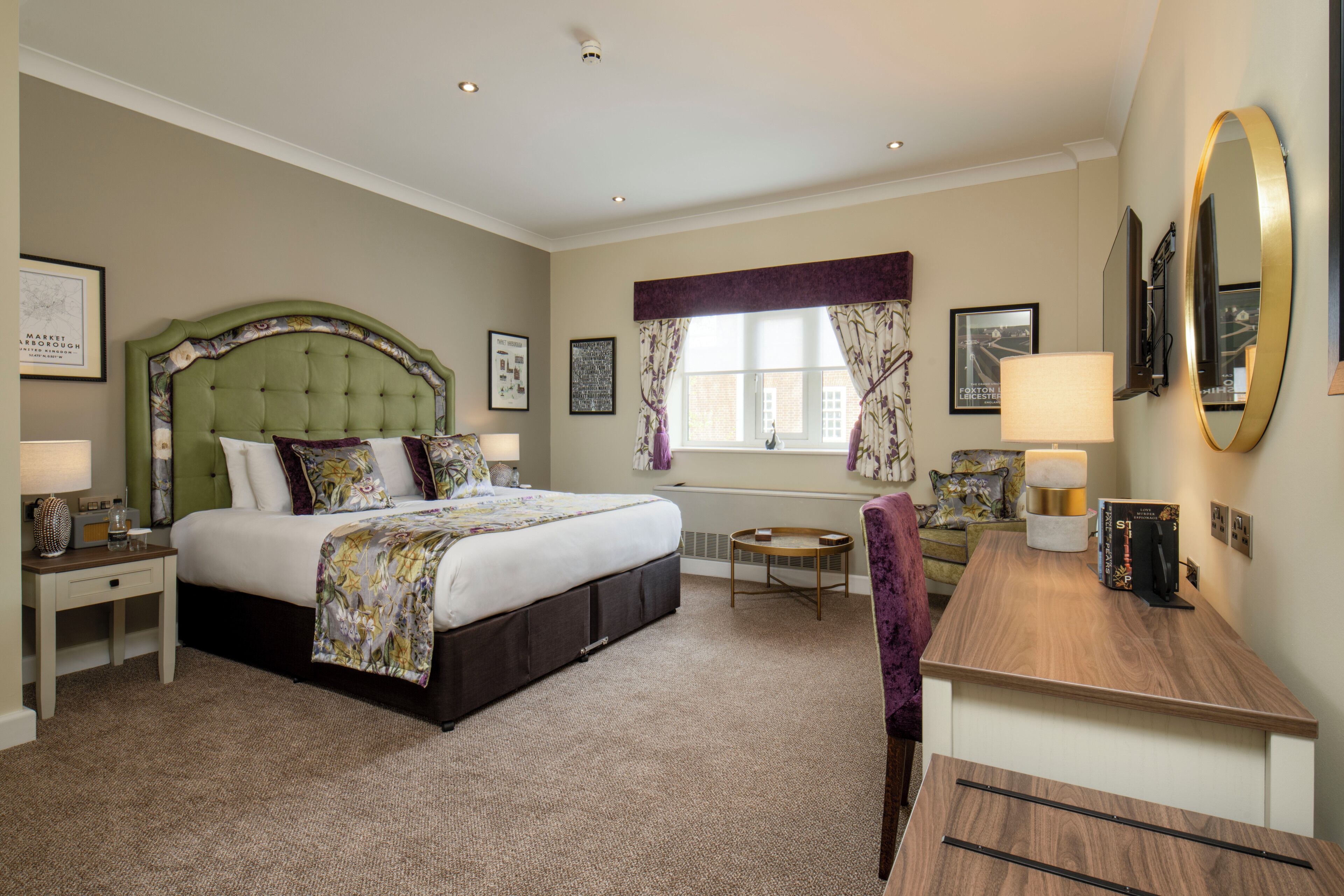 A hotel room with a large bed, a desk, a chair, a round table, and a window with curtains.