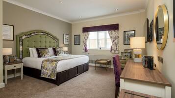 A hotel room with a large bed, a desk, a chair, a round table, and a window with curtains.