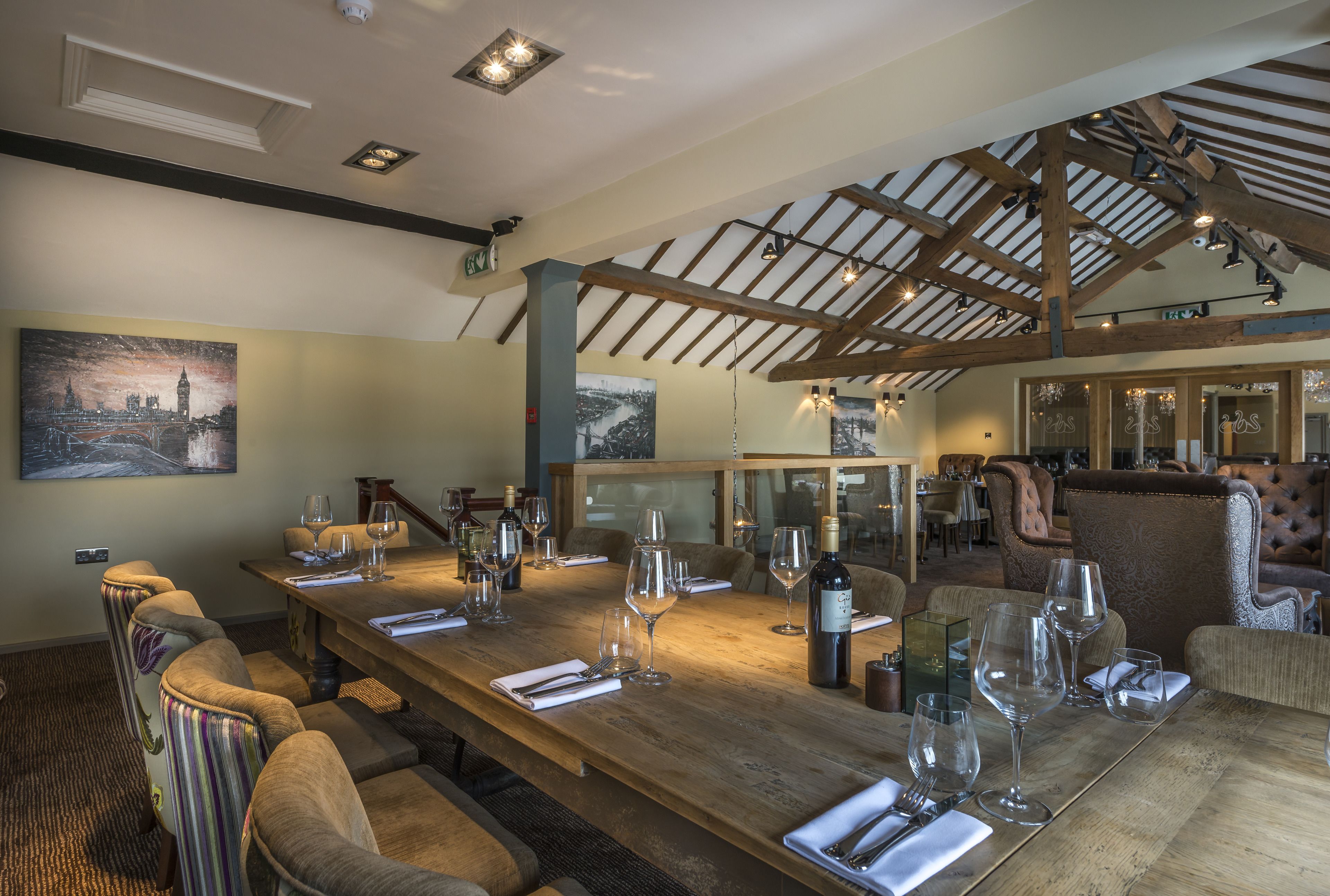 A dining area with a long wooden table set for a meal, surrounded by upholstered chairs.