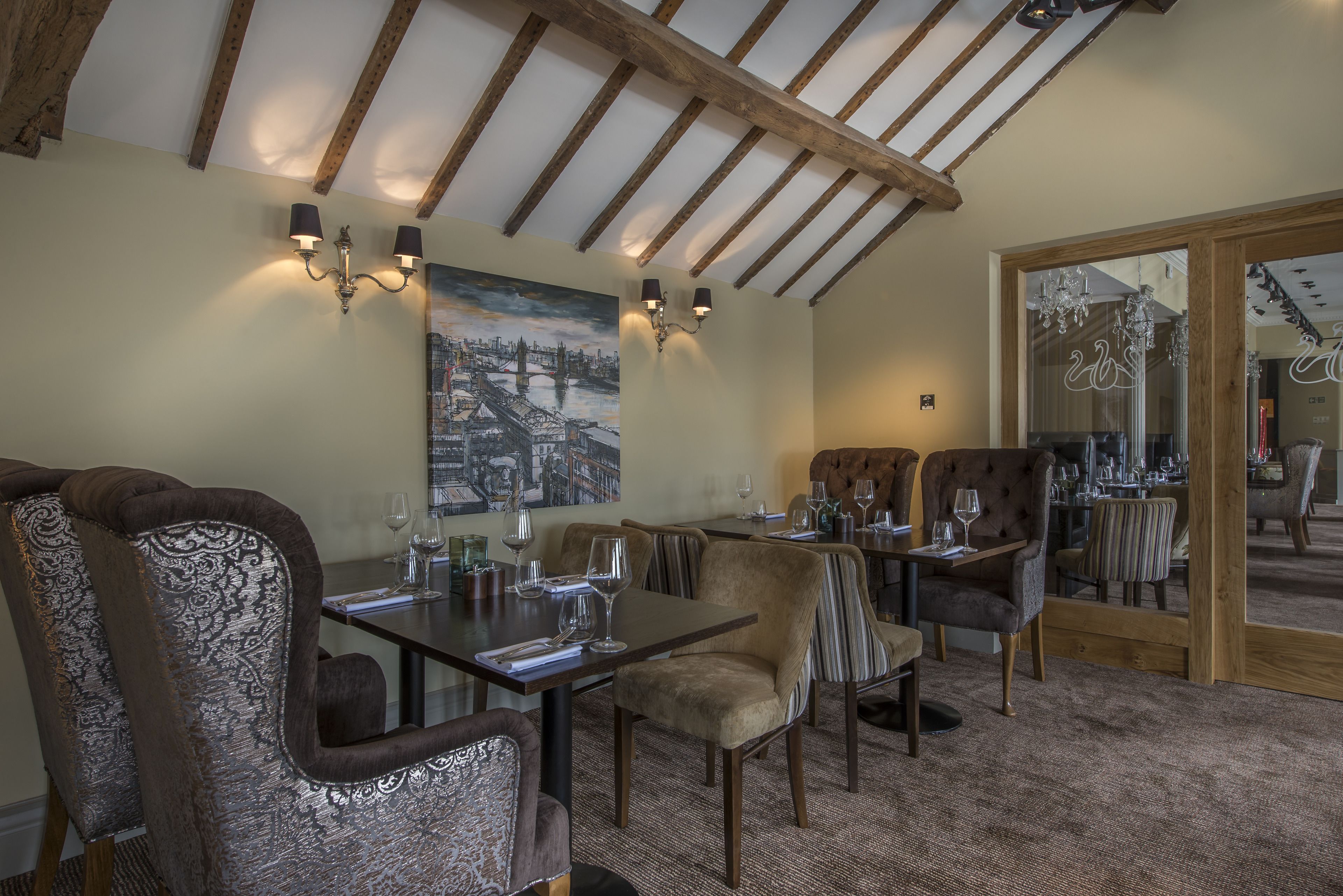 A dining area with wooden beams, cushioned chairs, and a cityscape painting on the wall.
