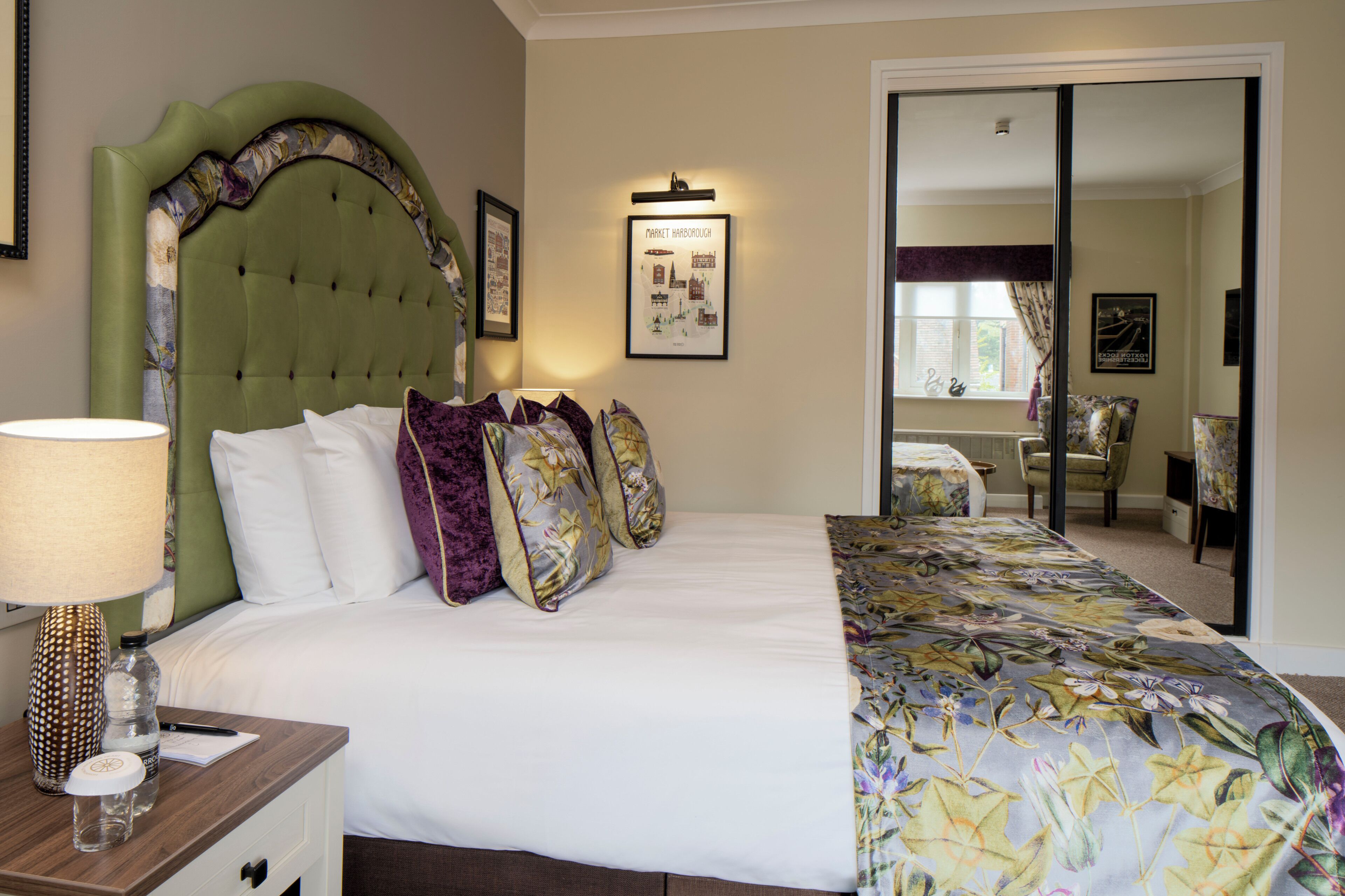 A hotel room with a large bed, a nightstand, a lamp, and a framed picture on the wall.