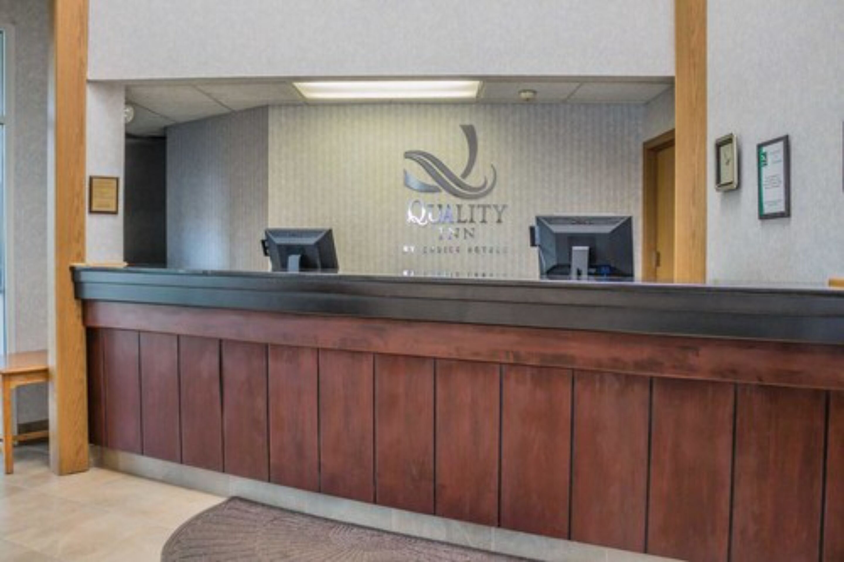 A reception desk with a logo and name "QUALITY INN" on the wall behind it.
