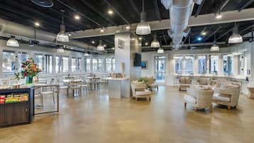 A spacious, well-lit lounge area with modern furniture, large windows, and a central island with seating.