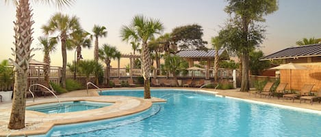 Una piscina con tumbonas y palmeras.
