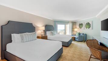 Habitación de hotel con dos camas, un escritorio, una silla y un balcón con vistas.