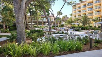 A courtyard with outdoor seating, surrounded by trees and a building with balconies.