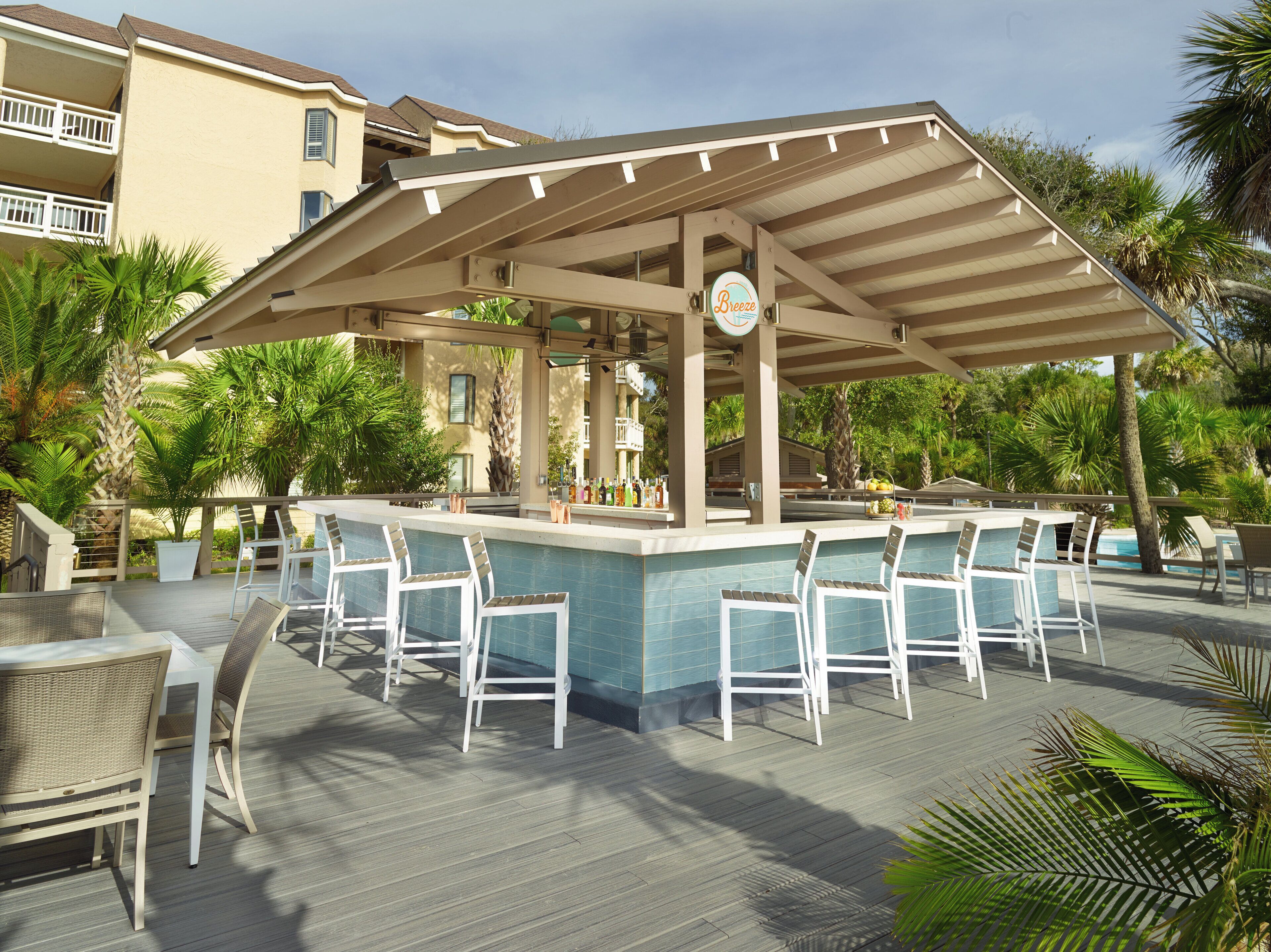 A poolside bar area with white chairs and a pool.