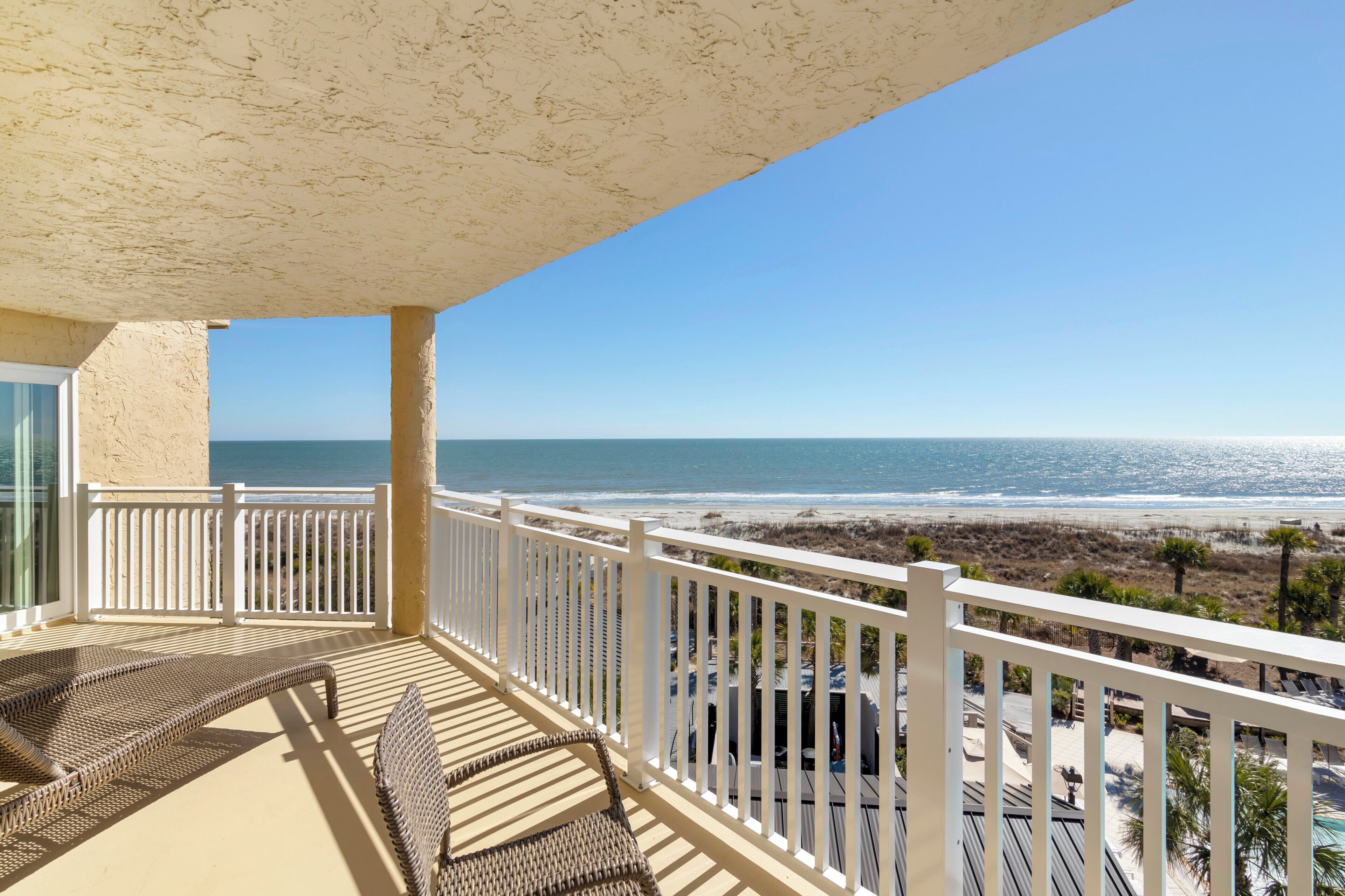 A balcony with a view of the beach and ocean.
