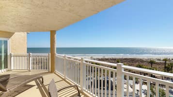 A balcony with a view of the beach and ocean.
