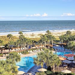 Relax by the pool surrounded by palm trees and enjoy stunning ocean views.