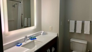 A bathroom with a large mirror, a sink with a faucet, a toilet, and a towel rack with towels.