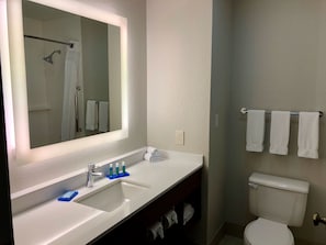 A bathroom with a large mirror, a sink with a faucet, a toilet, and a towel rack with towels. - Holiday Inn Express Arlington by IHG (Arlington)