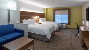 A hotel room with a bed, a desk, a chair, a sofa, and a lamp.