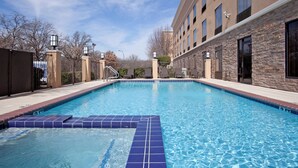 A swimming pool with a tiled edge, surrounded by a building with stone facade and windows. - Holiday Inn Express Arlington by IHG (Arlington)
