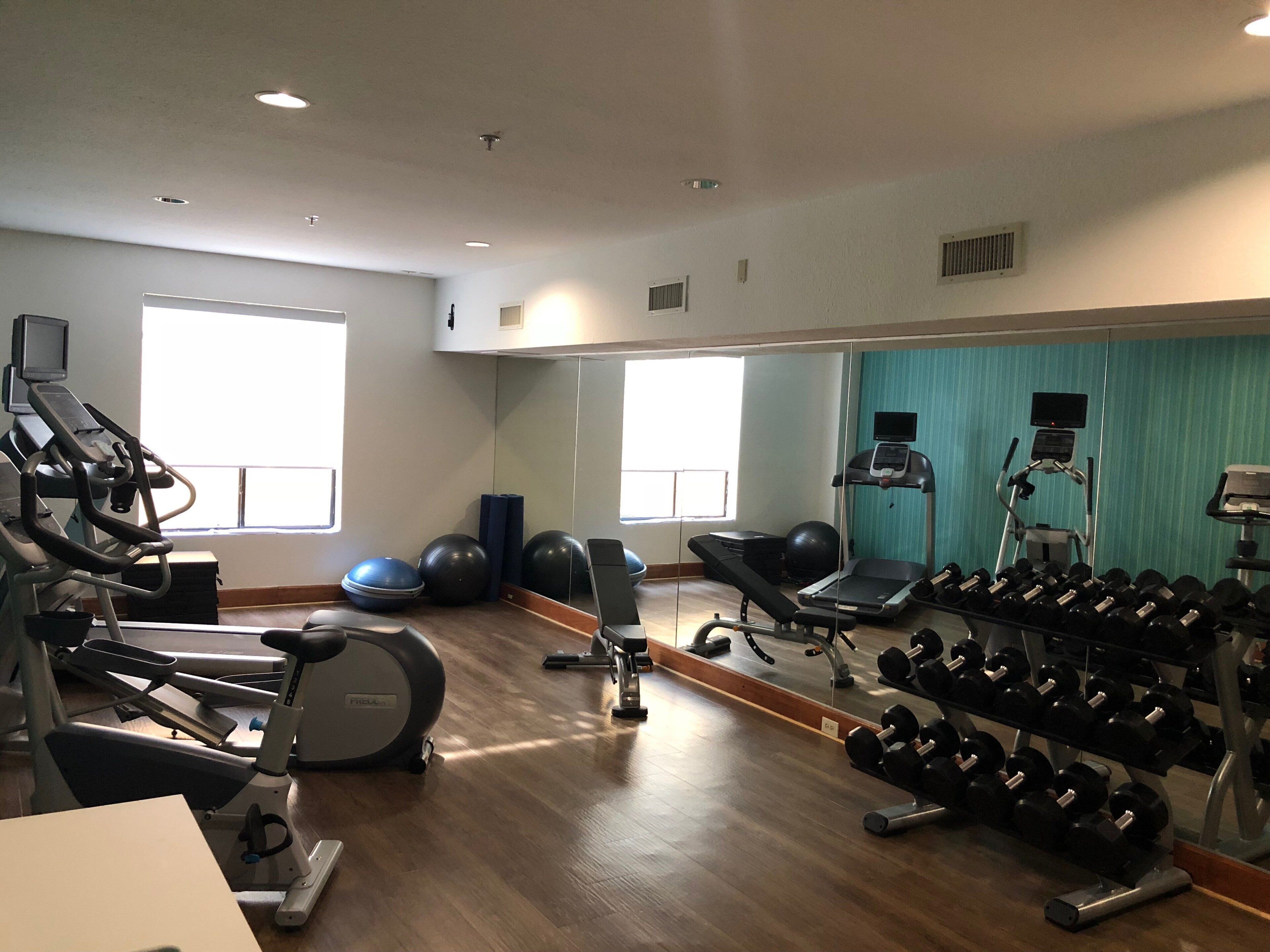 A gym with exercise equipment, a mirror, and a window.