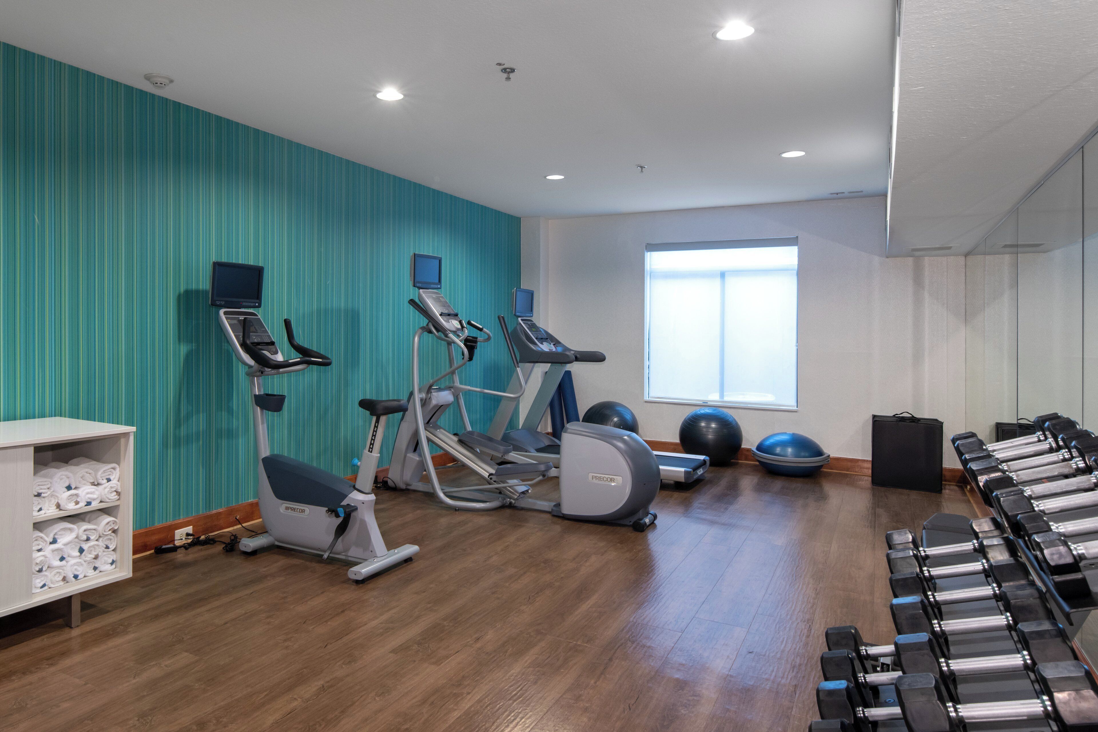 A gym with cardio machines, free weights, and exercise balls.