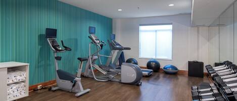 A gym with cardio machines, free weights, and exercise balls.