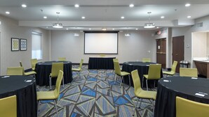 A conference room with round tables, chairs, a projector screen, and a carpeted floor. - Holiday Inn Express Arlington by IHG (Arlington)