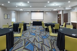 A conference room with round tables, chairs, a projector screen, and a carpeted floor. - Holiday Inn Express Arlington by IHG (Arlington)