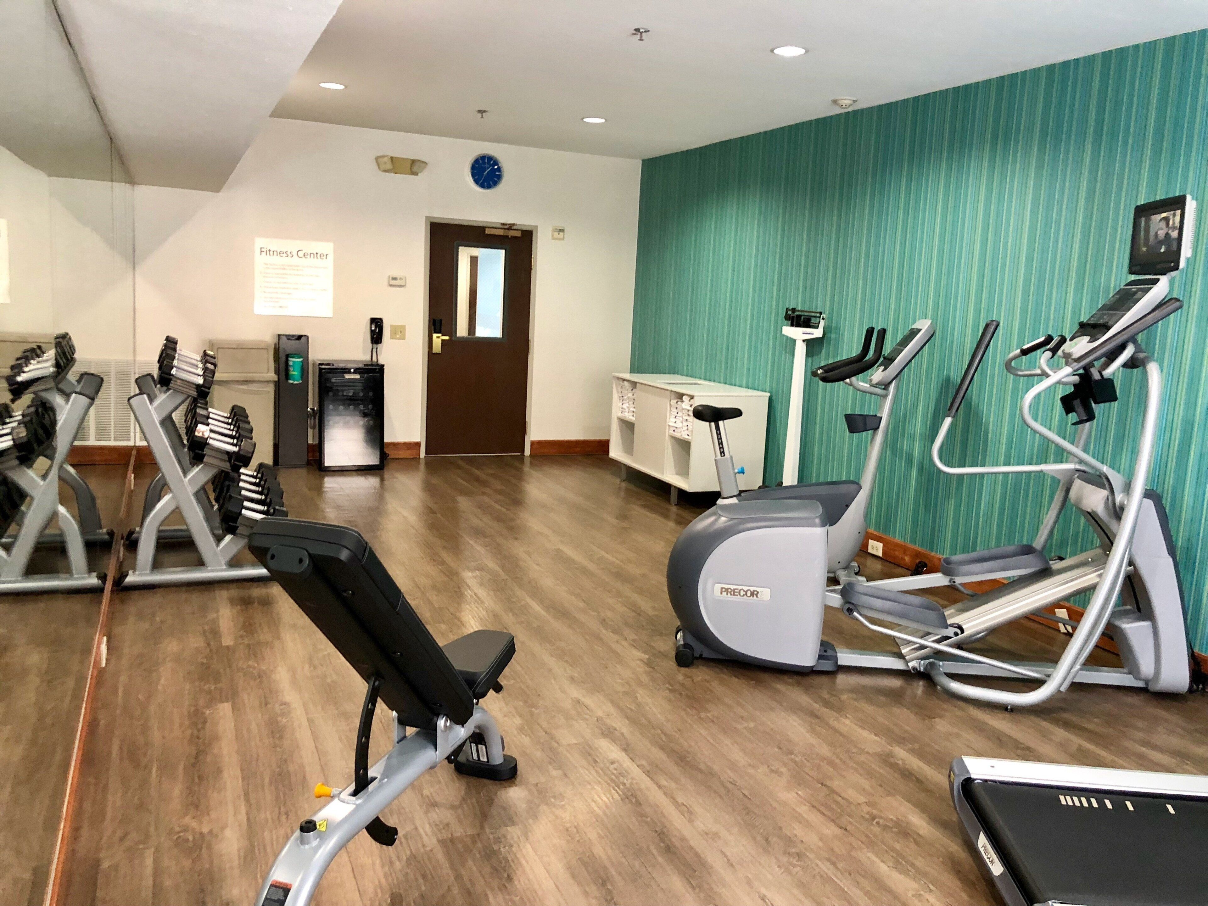 A fitness center with various exercise equipment, including treadmills and weight machines, and a sign indicating the location.